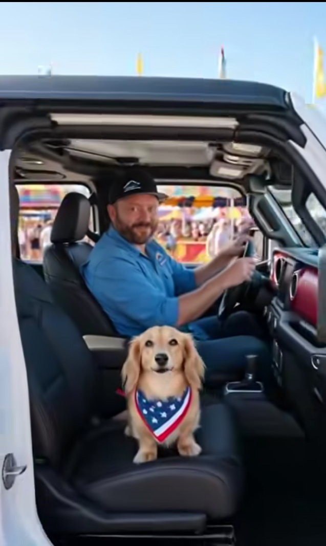 Robert Hall driving a white Jeep Wrangler with Dude, his blonde long-haired dachshund, in the passenger seat.